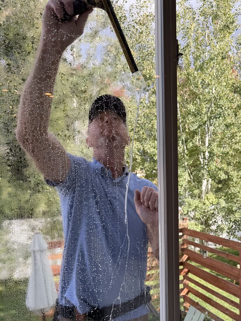 Wes squeegeeing a sliding door, seen through the glass